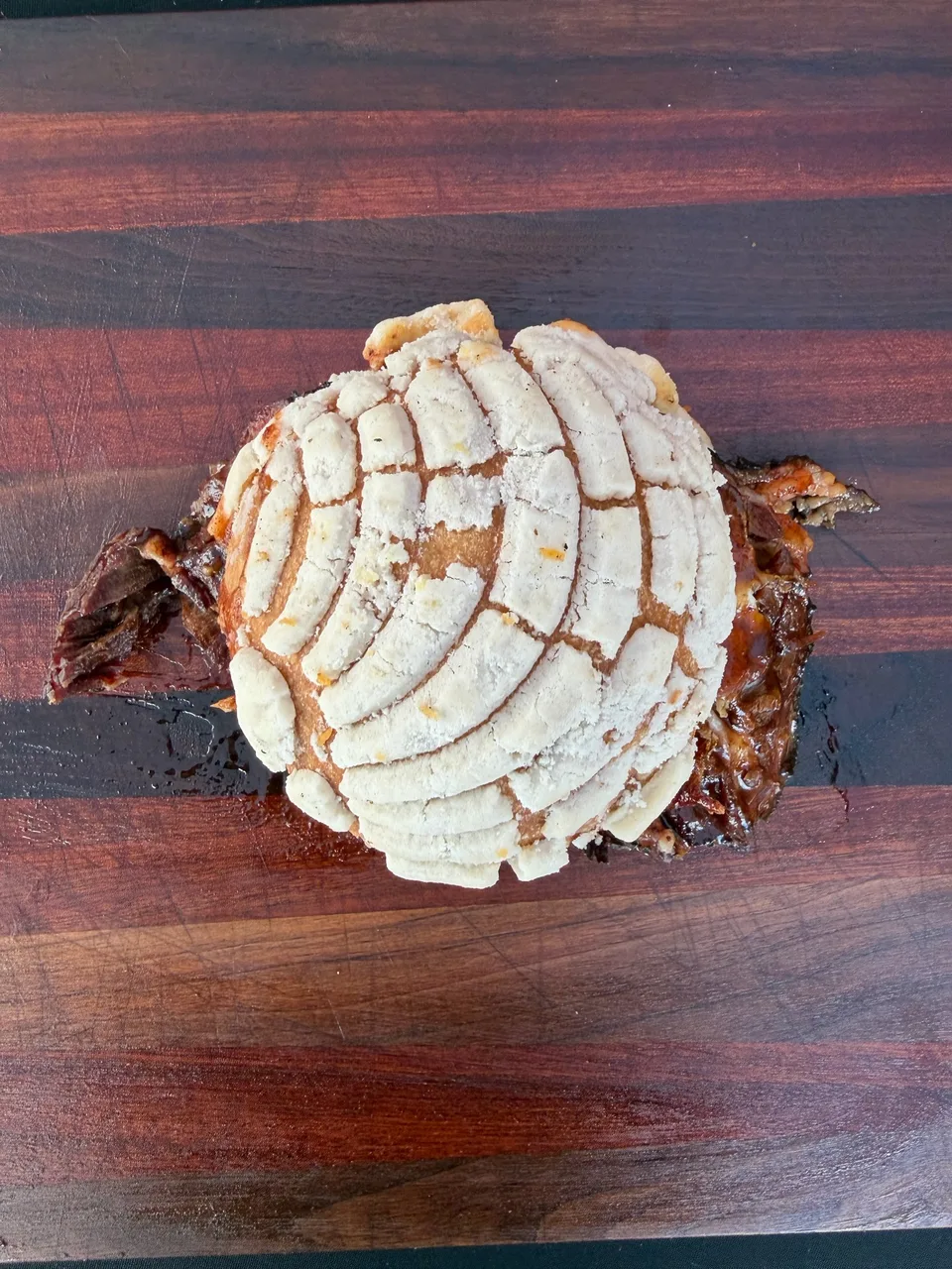 Brisket sandwich in a concha on a wooden cutting board