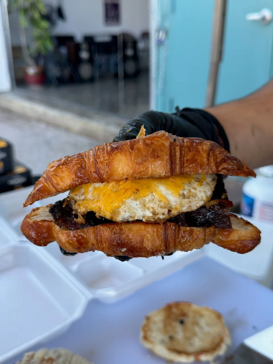 Croissant sandwich filled with smoked meat, egg, and melted cheese