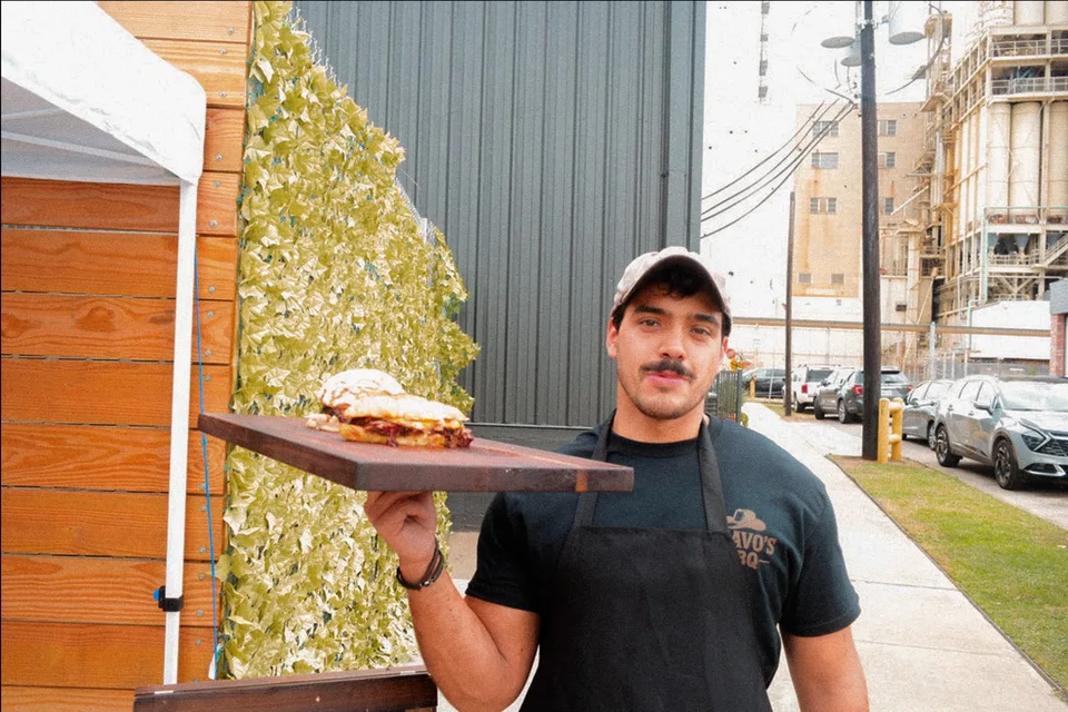 Ivan holding a board with a barbecue sandwich